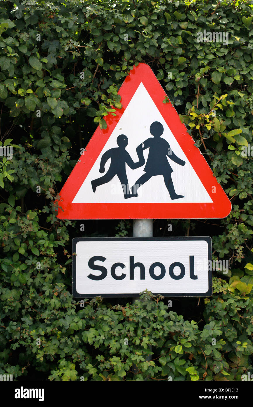 School warning sign against a green hedge Stock Photo