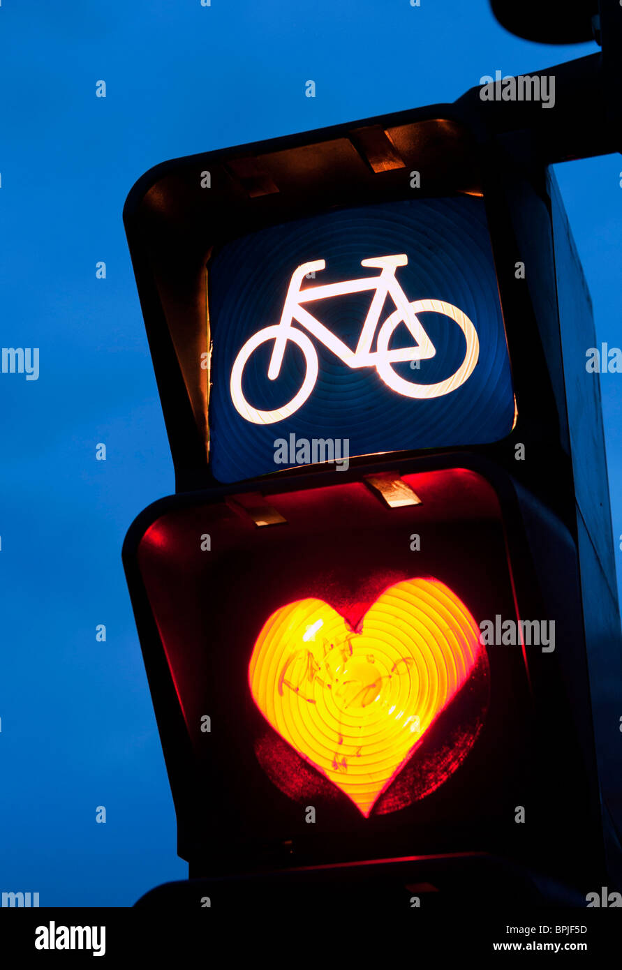 Detail of red cycle traffic stop light painted with love heart in Berlin Germany Stock Photo