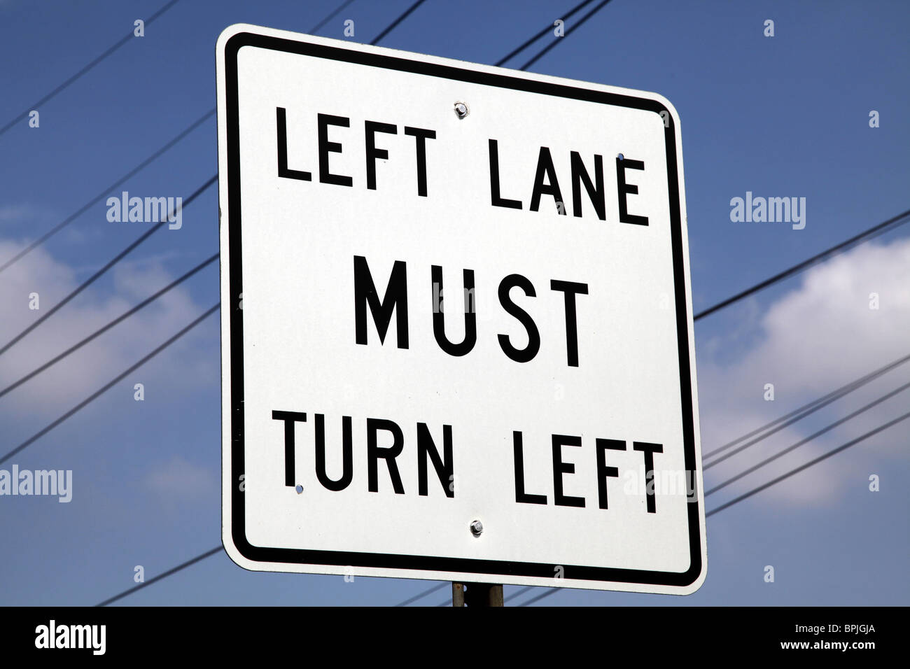 Left Lane MUST turn Left. American road sign Stock Photo