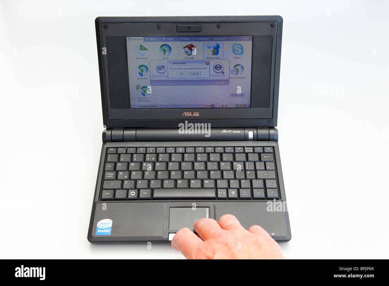 Mature person's hand using a small Asus netbook EEE PC computer running Linux operating system showing shut down screen. Stock Photo