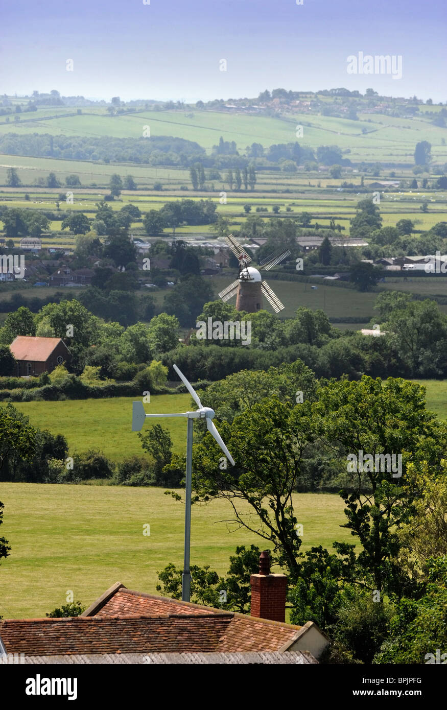 A wind turbine in the garden of a family home with the traditional windmill at Quainton in the distance in Buckinghamshire UK Stock Photo