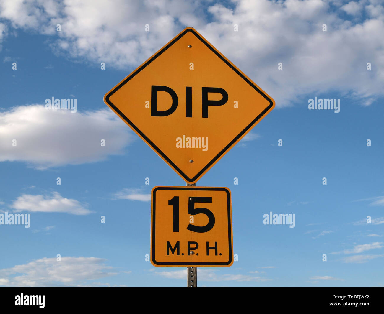 Dip ahead caution sign with a bight blue sky. Stock Photo