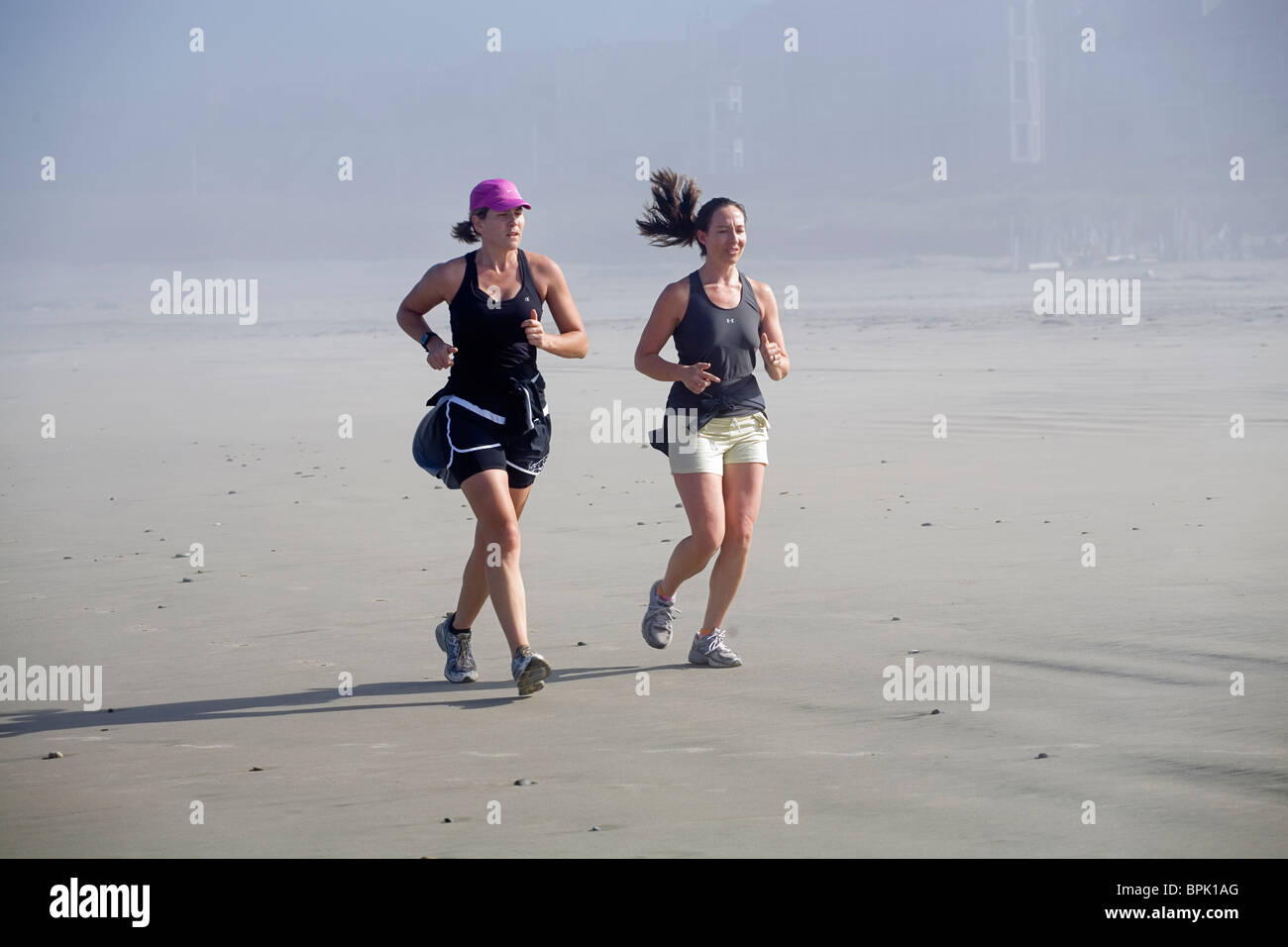 Two women running on a beach near Manzanita, Oregon, on the Oregon Pacific Coast. Stock Photo