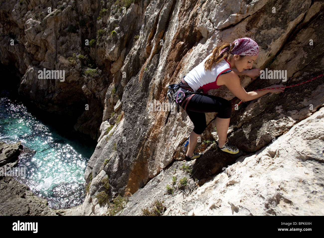 A young woman, a climber, a sportclimber, freeclimber, climbing on the cliffs at the bay of Zurrieq, Malta, Europe Stock Photo