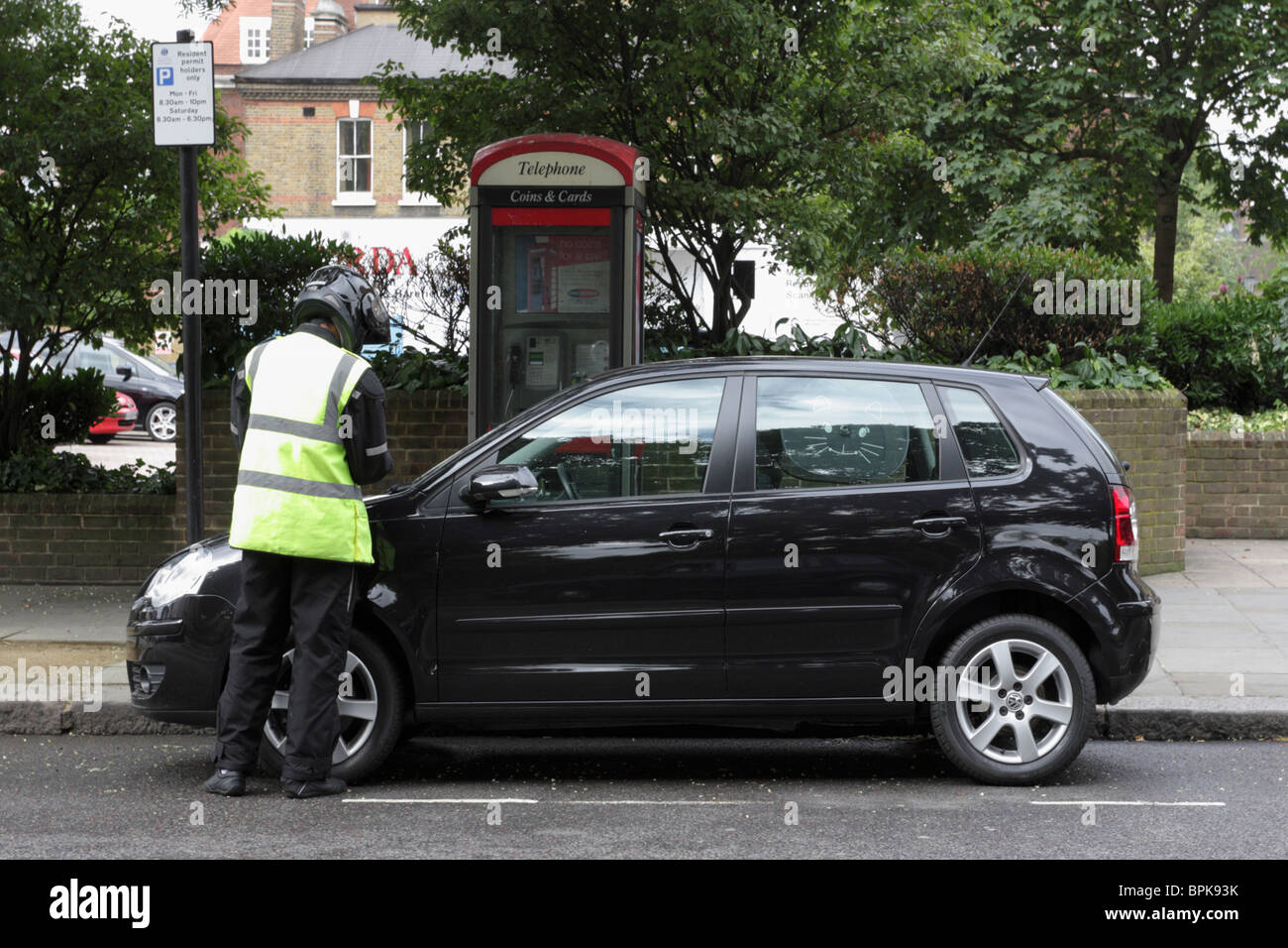 London Traffic Warden issuing a PCN upon a vehicle in Sydney Street, Chelsea, London. Stock Photo