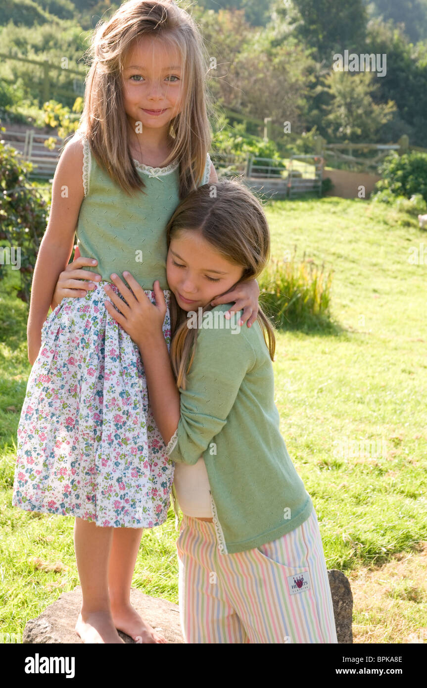 Two girls hugging playing outside on a summers day Stock Photo - Alamy