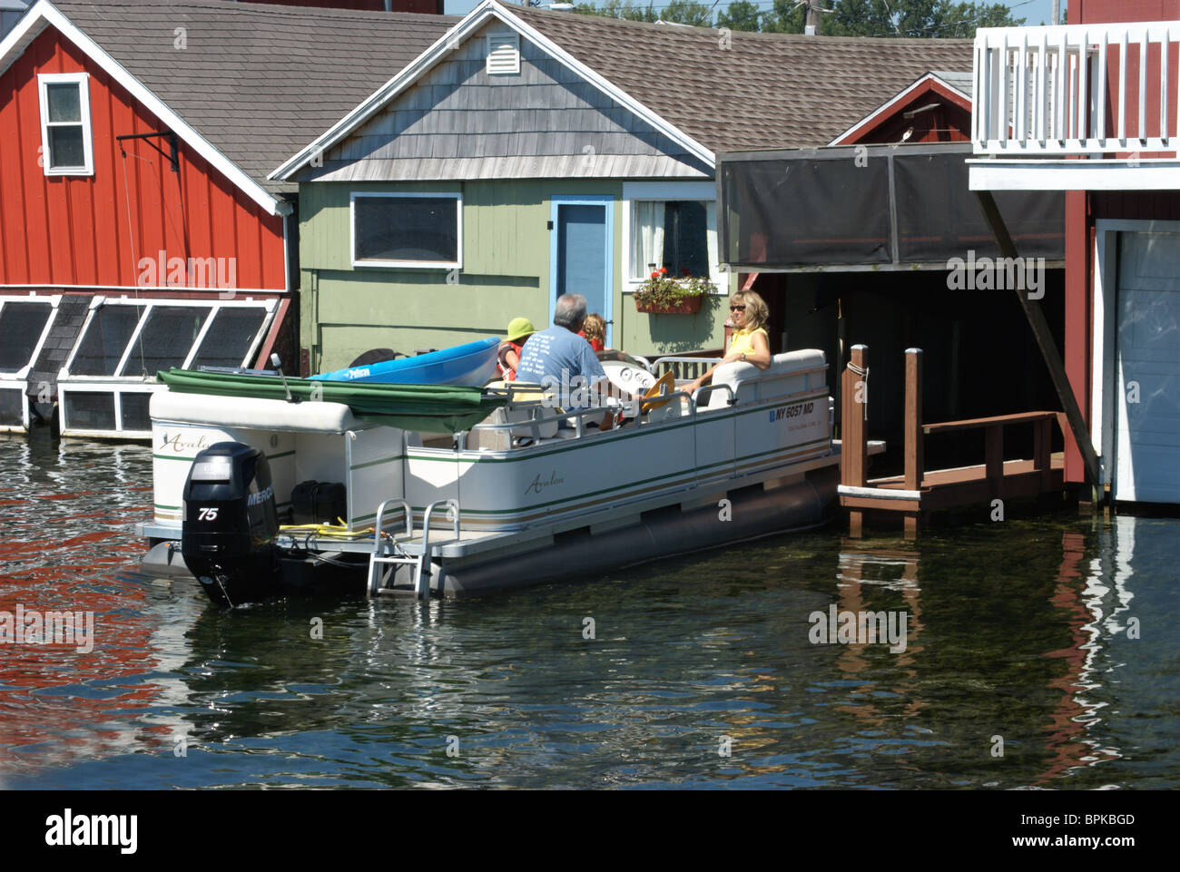 Family backs pontoon craft out of boat house for excursion on Lake