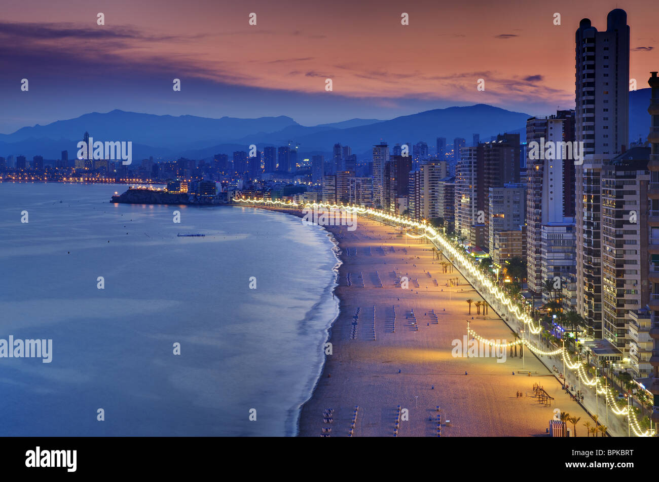 Attractive aerial view of Benidorm's Levante beach at sunset, with its buildings facade and lighted promenade on the right. Stock Photo