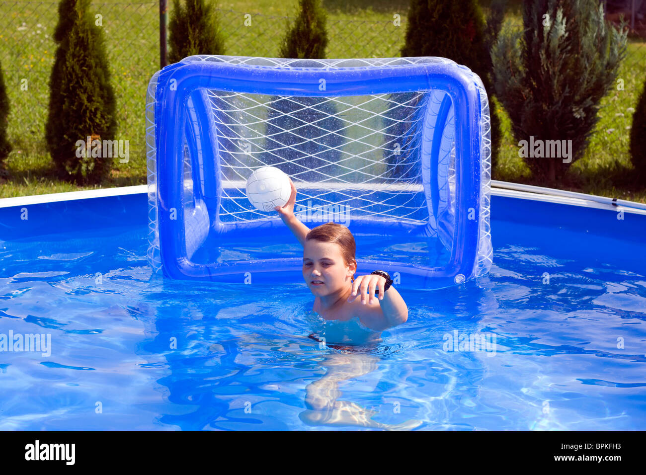 Teenager playing water polo in garden pool. Stock Photo