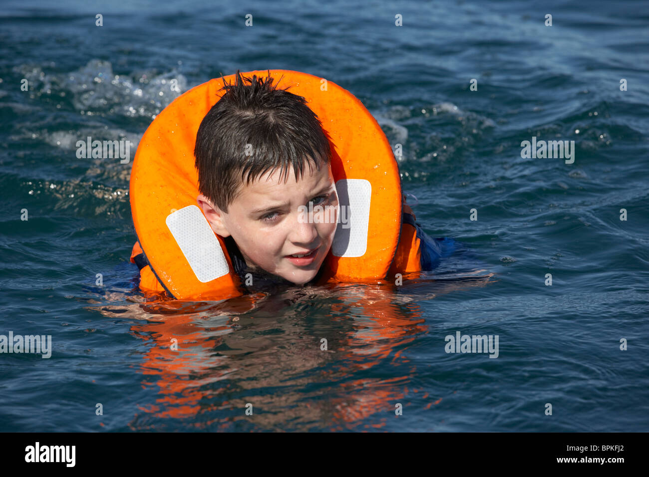 10 year old boy wearing lifejacket swimming in the sea Stock Photo