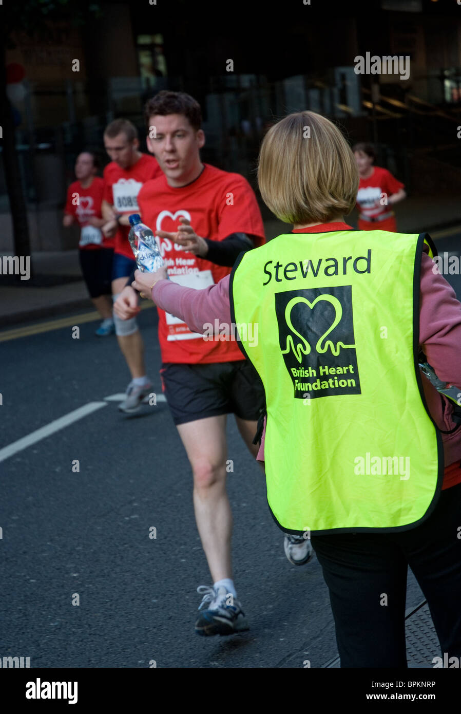 steward hands out water for charity runners Stock Photo