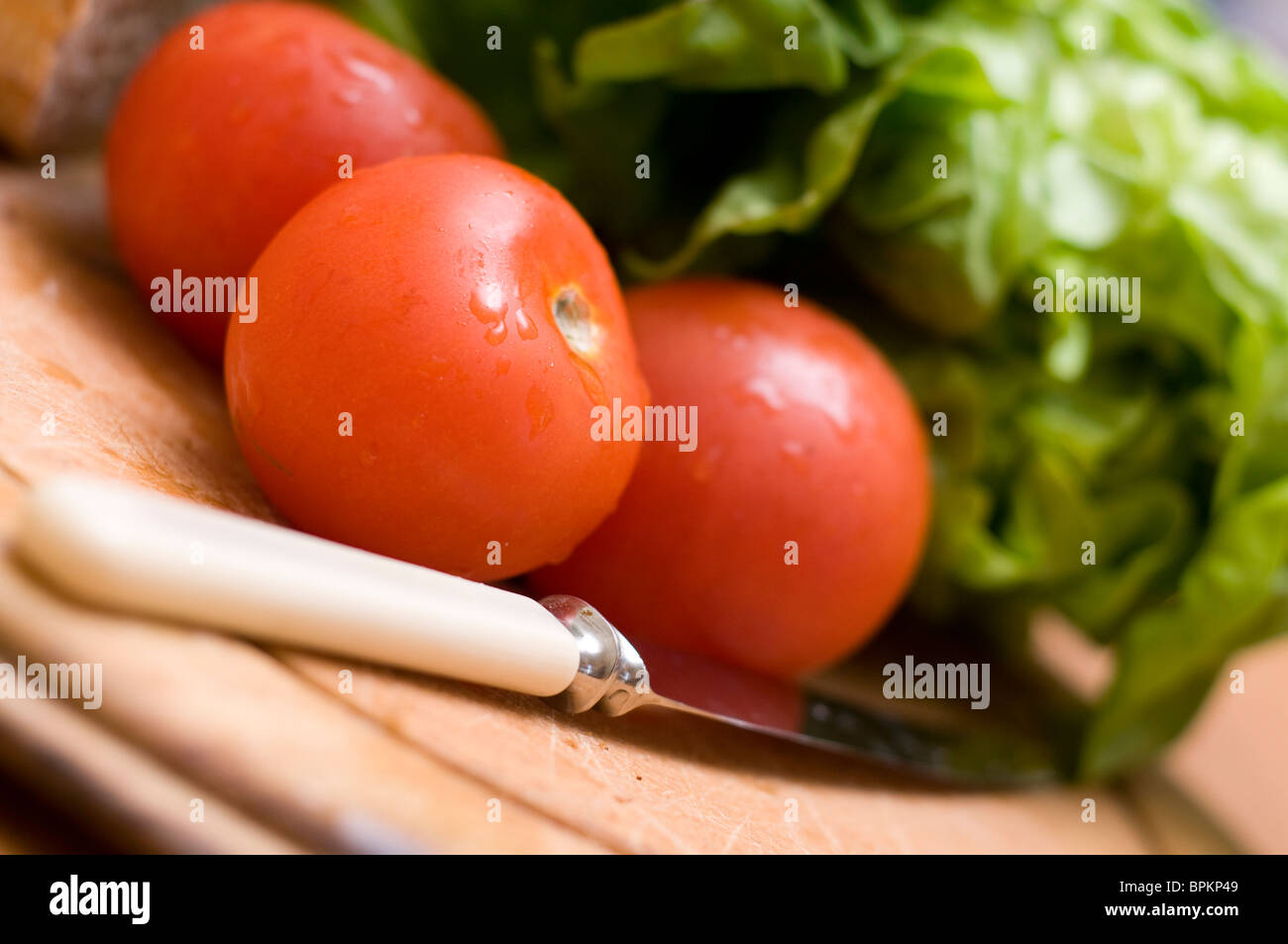 Tomatoes green lettuce and a knife and a chopping board Stock Photo - Alamy