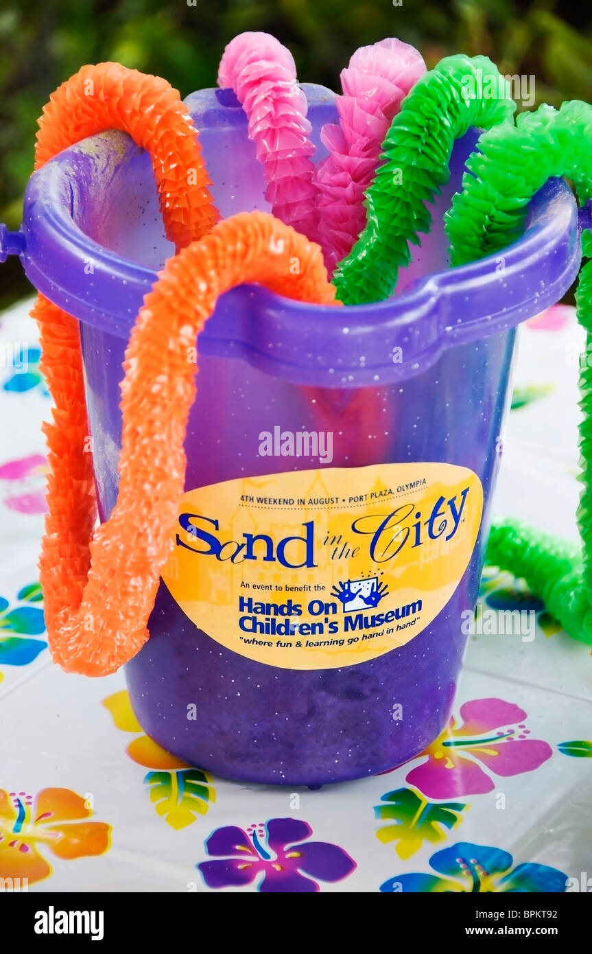 A purple beach bucket filled with colorful plastic leis decorates a table at the Sand in the City community event in Olympia, WA Stock Photo