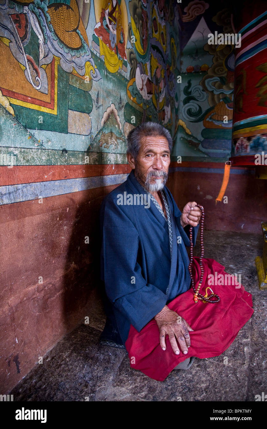 A Bhutanese man in prayer at the prayer wheel at Chimi Lakang Bhutan Asia Stock Photo