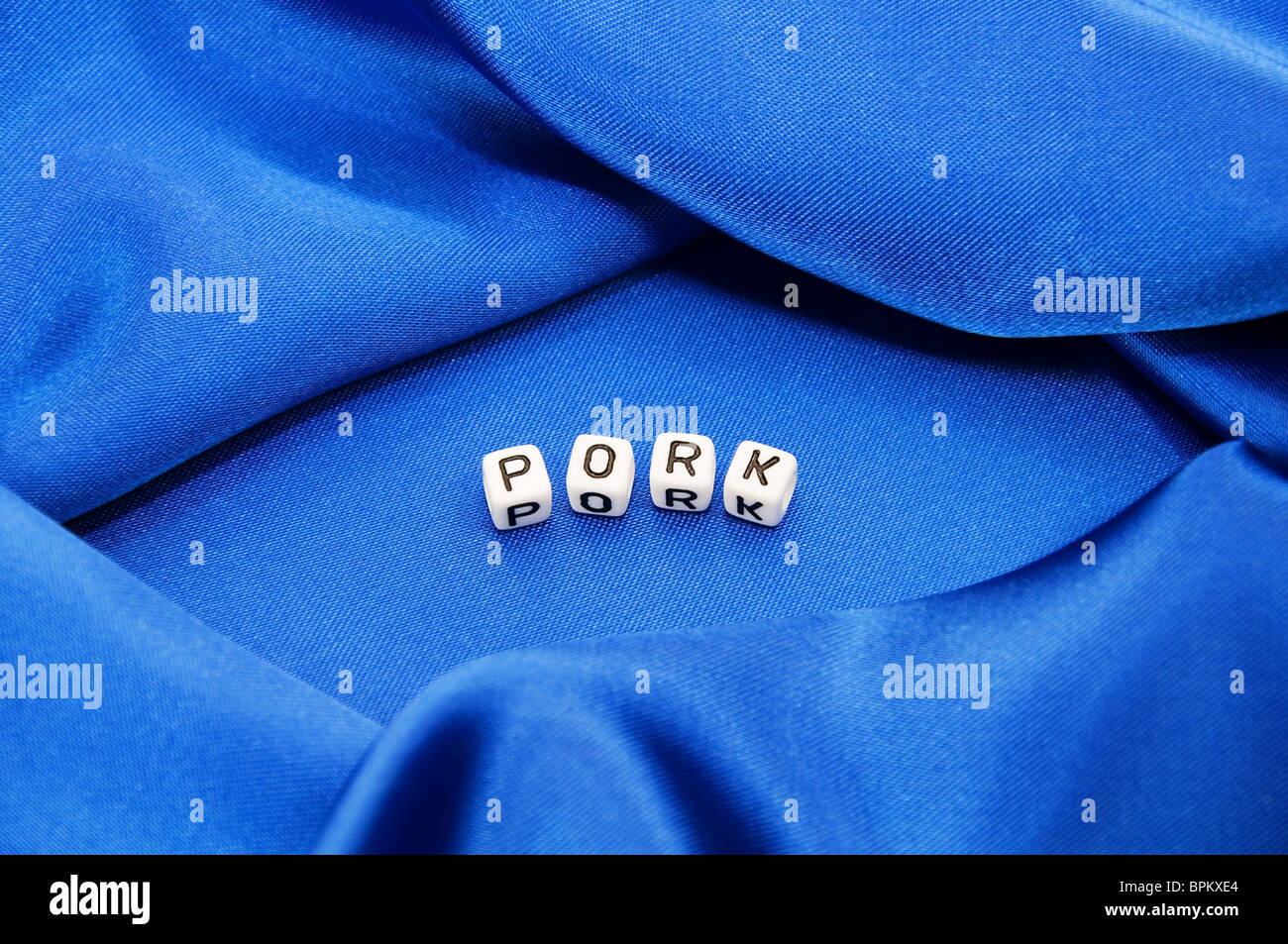Royal blue satin background with rich folds and wrinkles for texture is the word pork in black and white cube lettering series Stock Photo