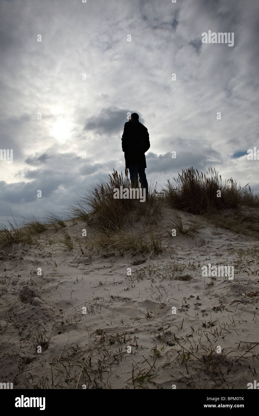 Silhouetted man standing on top of sand dune Stock Photo - Alamy