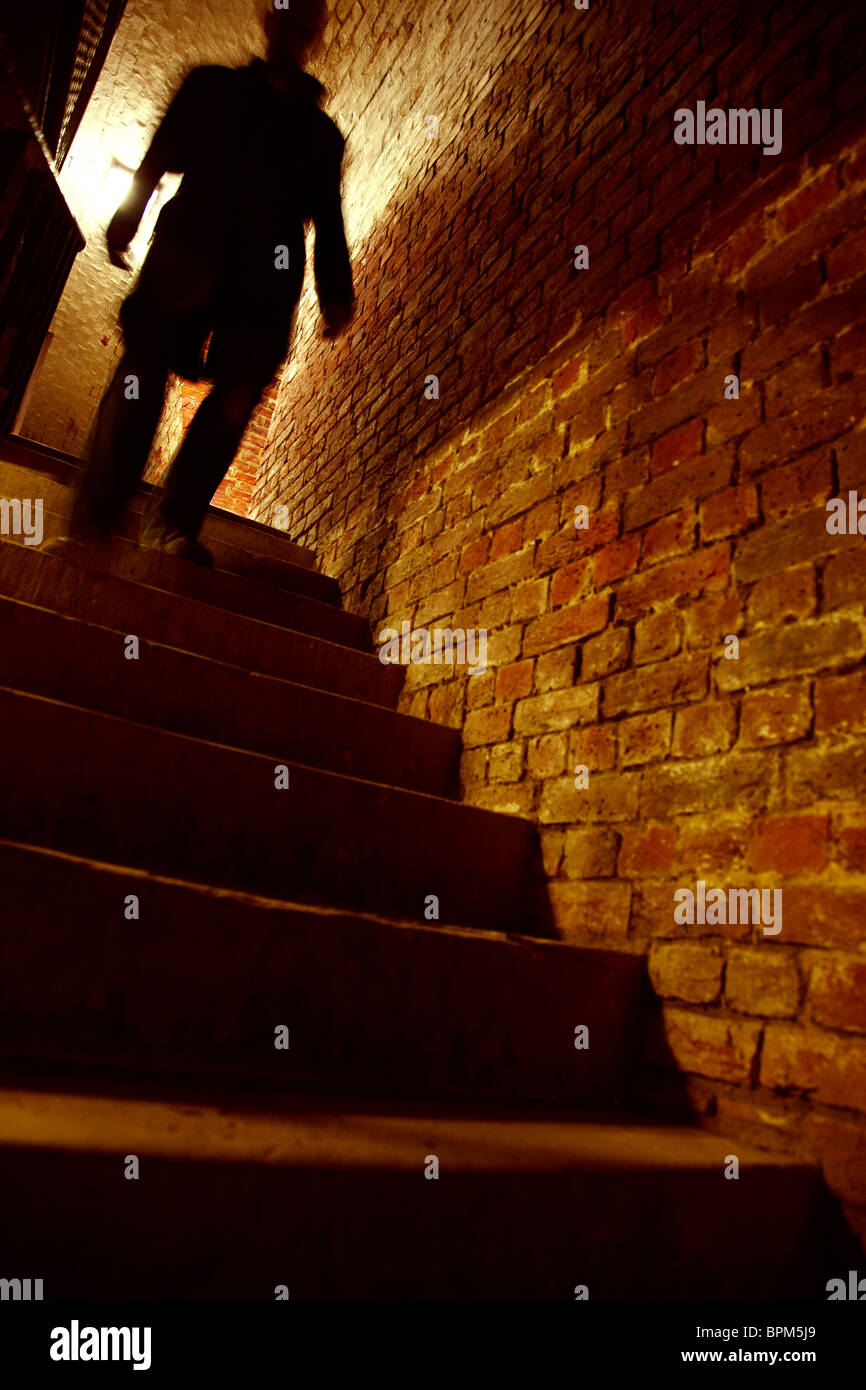 Silhouetted man walking down stairs Stock Photo