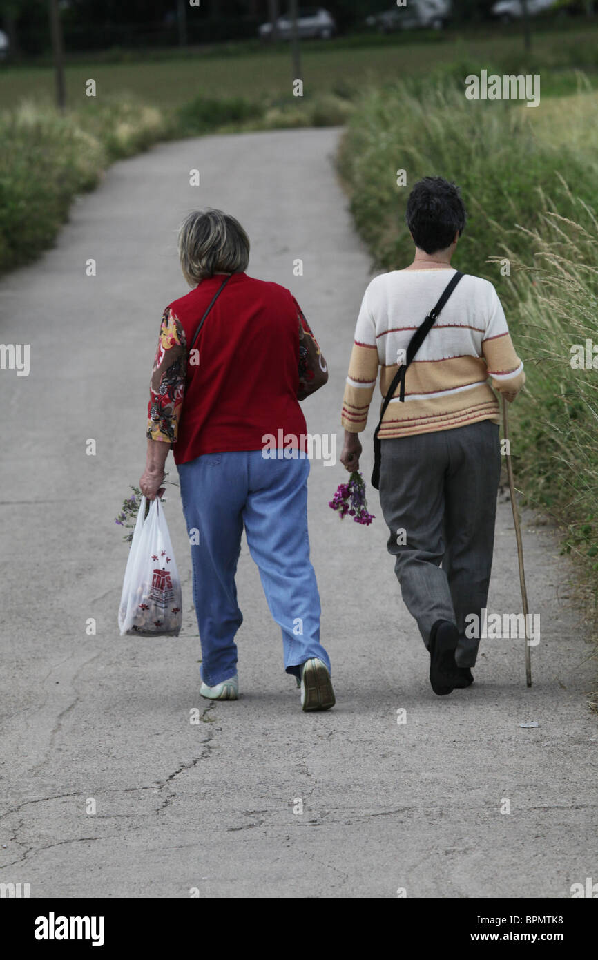 Two women picking flowers walking down a country road in Catalonia Spain Stock Photo