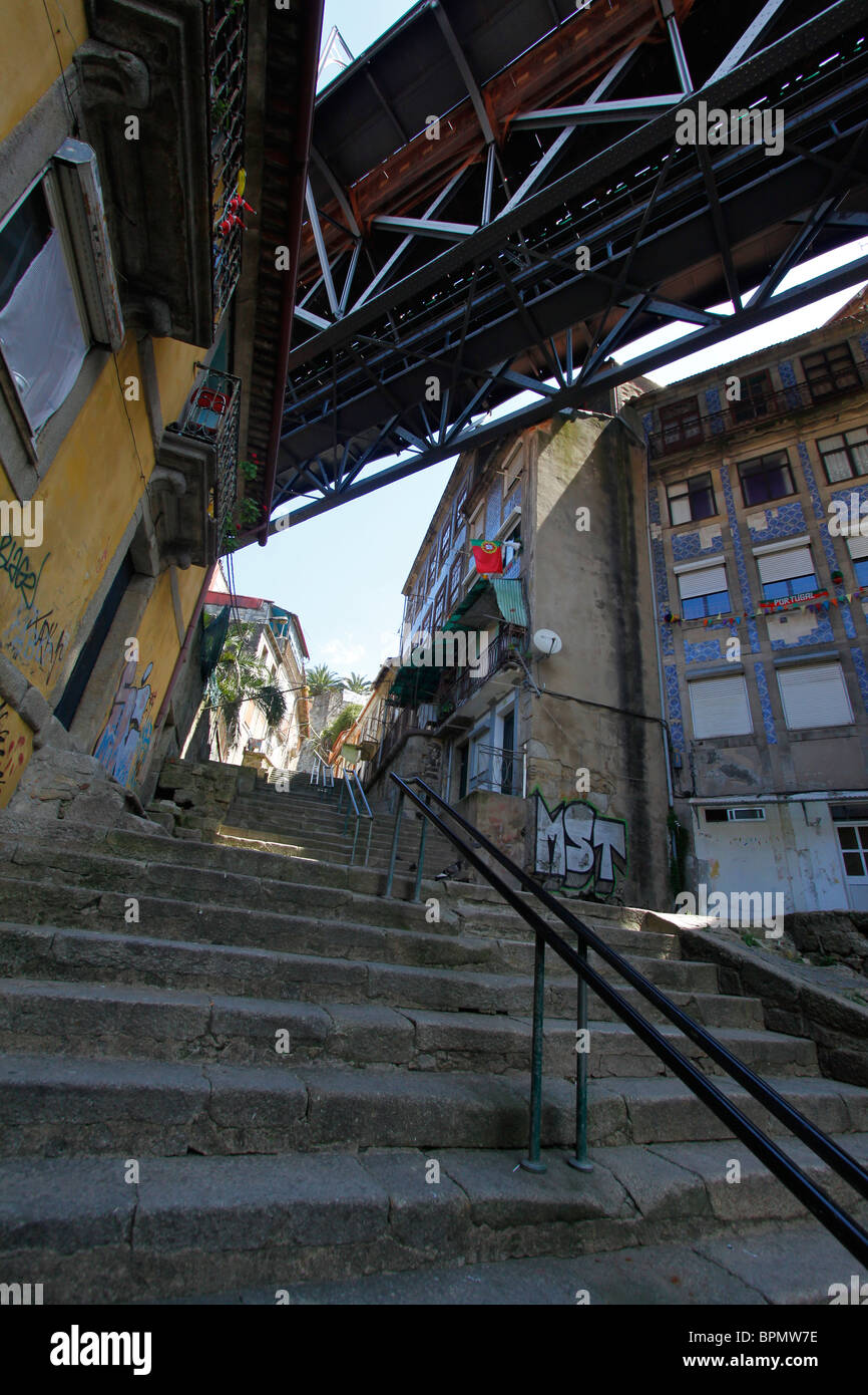 Portugal Street Scene with Uphill Steps, Old Buildings and Railway Bridge Stock Photo
