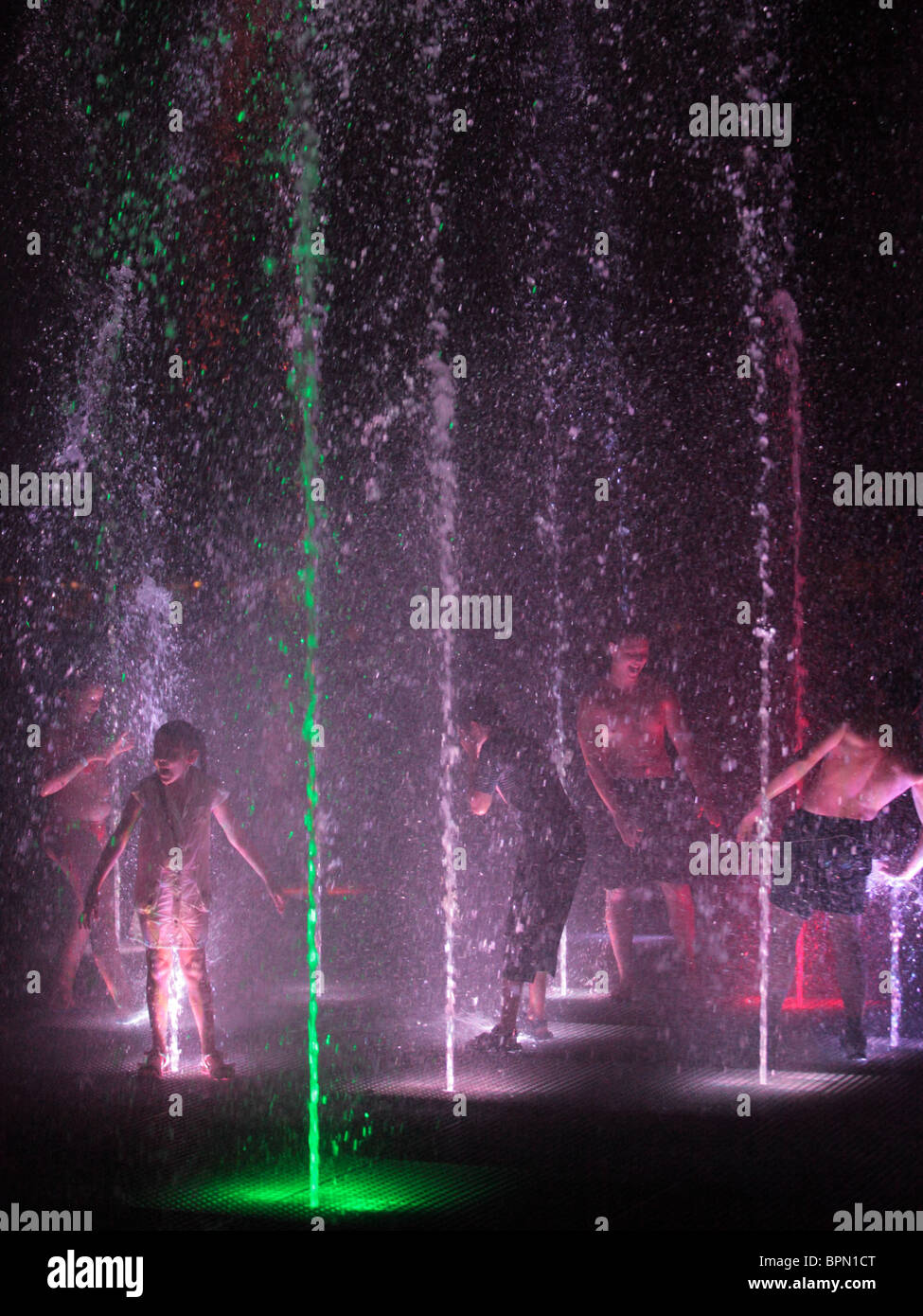 Kids playing in water jets, at night Stock Photo