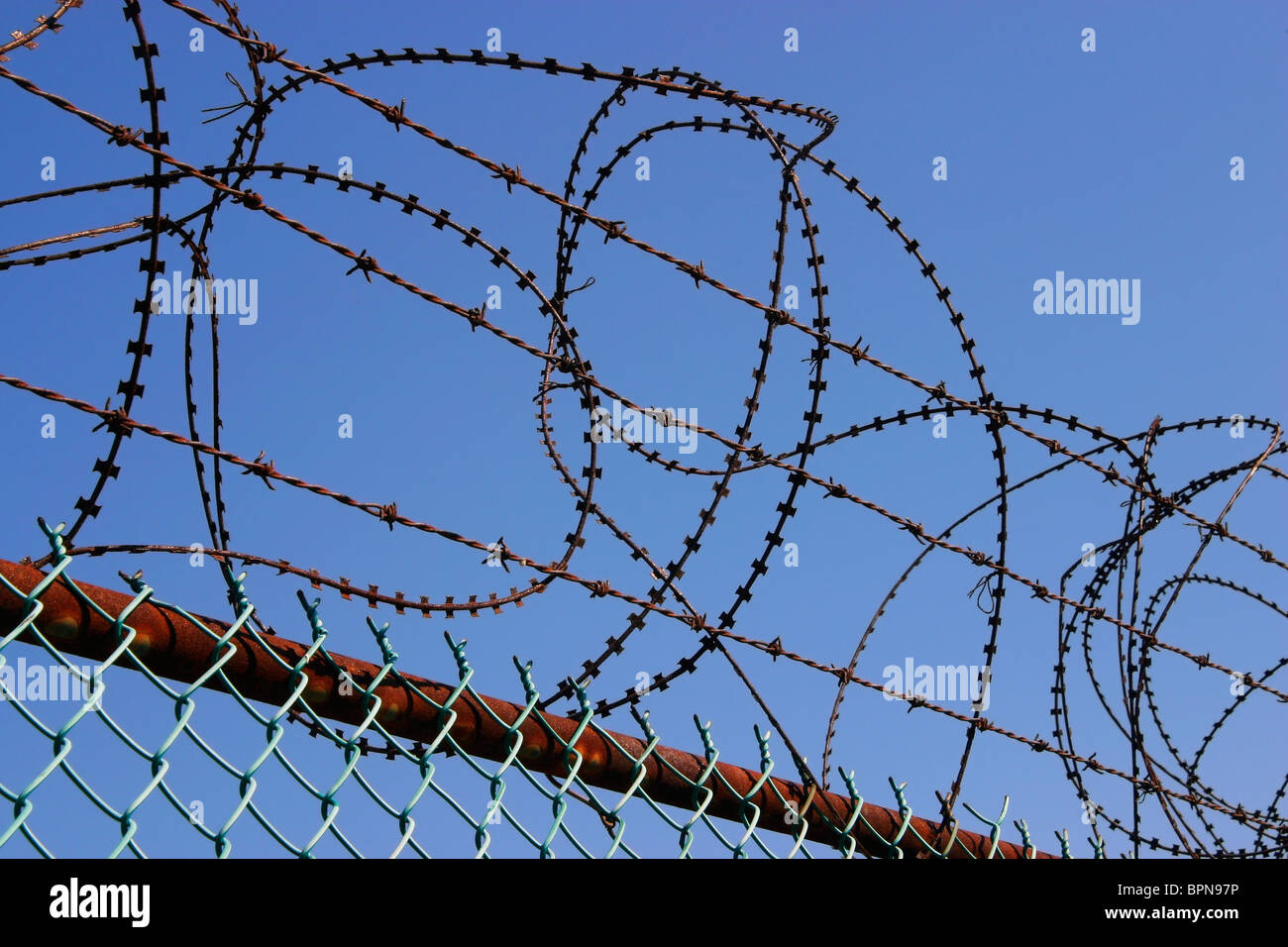 Razor wire, barbed wire, and chain-link fencing restrict entry. Stock Photo