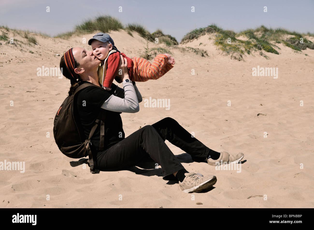 Mother with her six months old baby playing at the beach sand Stock Photo
