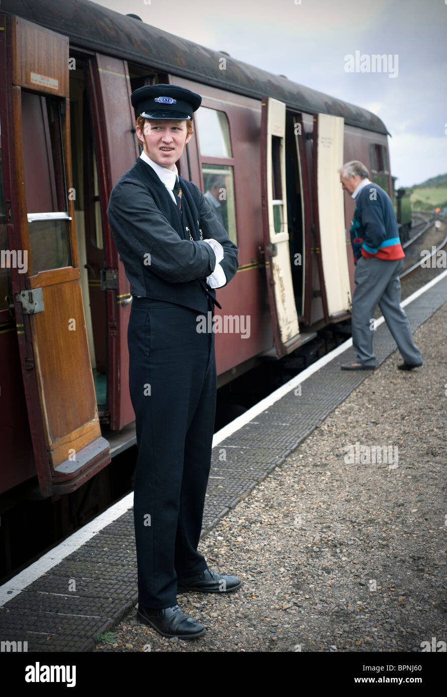 porter waiting beside train on poppy line north norfolk england Stock Photo