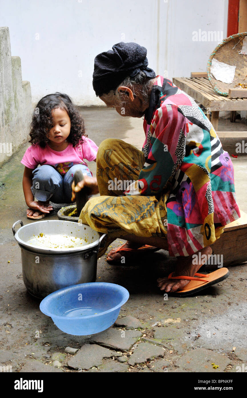young girl watches her elderly relative making a traditional medicine by hand Stock Photo