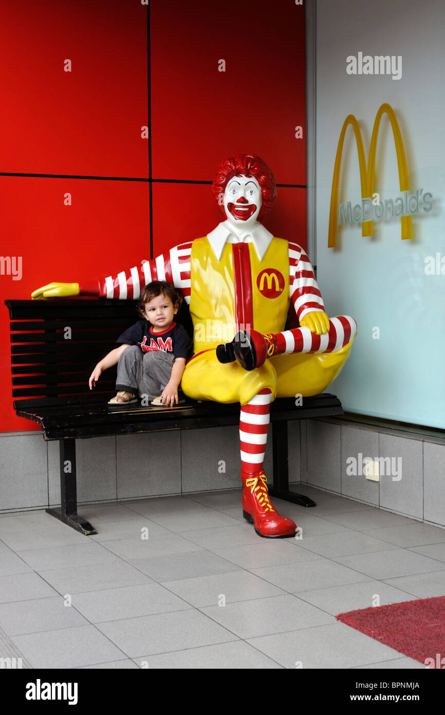 young boy getting close and affectionate with ronald mcdonald effigy Stock Photo