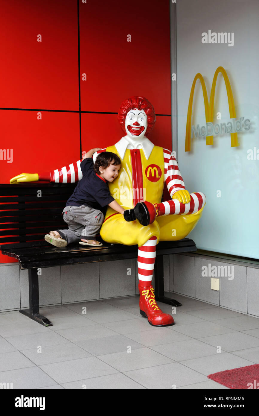 young boy getting close and affectionate with ronald mcdonald effigy Stock Photo