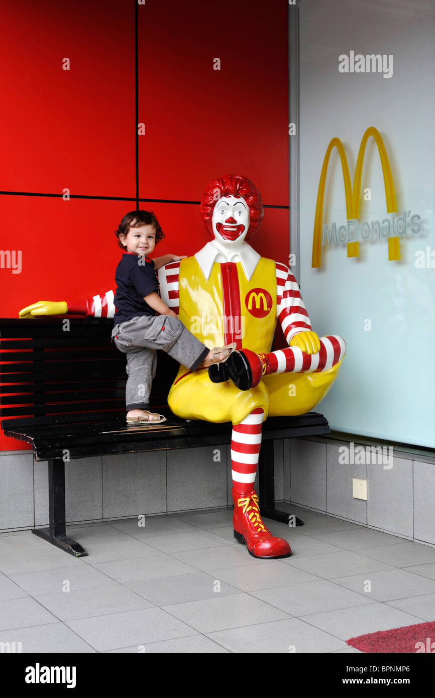 young boy getting close and affectionate with ronald mcdonald effigy Stock Photo