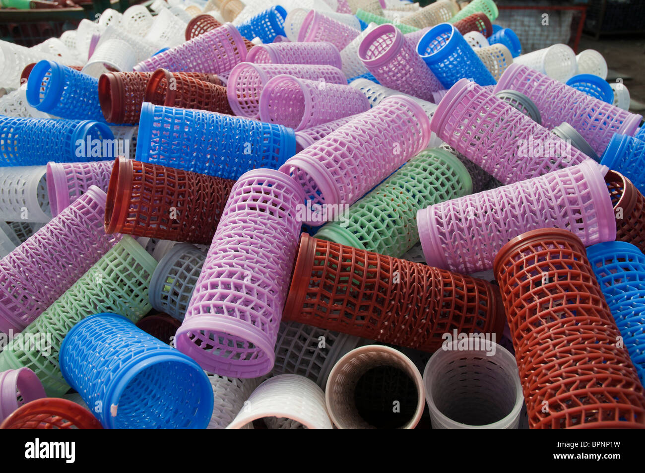 Plastic hair curlers stockpiled for recycling at a recycling plant Stock Photo