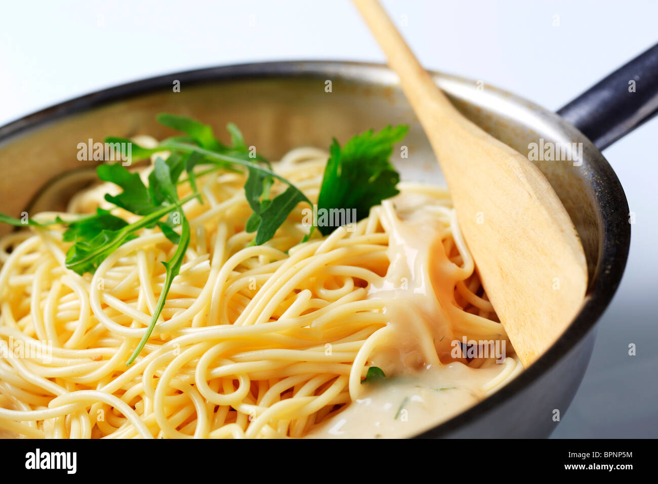 Stirring spaghetti and cheese sauce in a saucepan Stock Photo