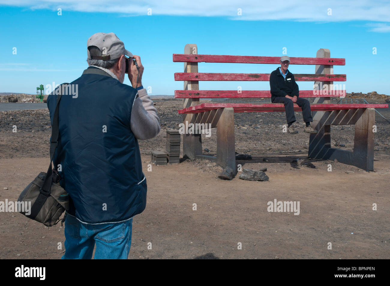 A tourist tries out a huge park bench in the New South Wales outback mining town of Broken Hill Stock Photo