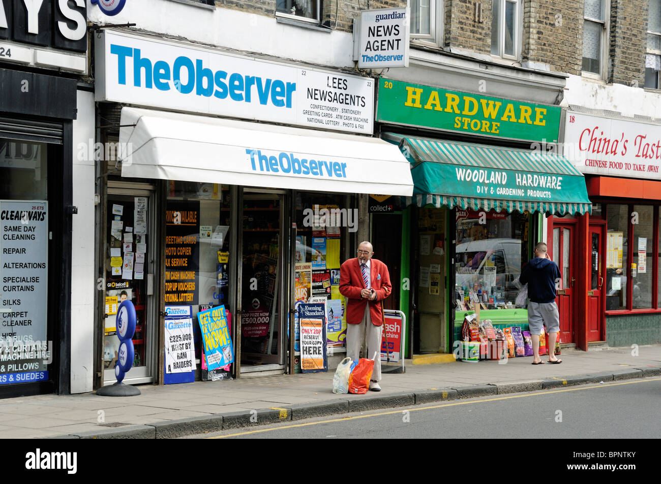 Man waiting outside newsagents with shopping bags, local shops Highbury