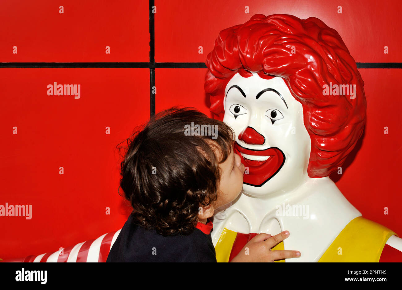 young boy getting close and affectionate with ronald mcdonald effigy Stock Photo