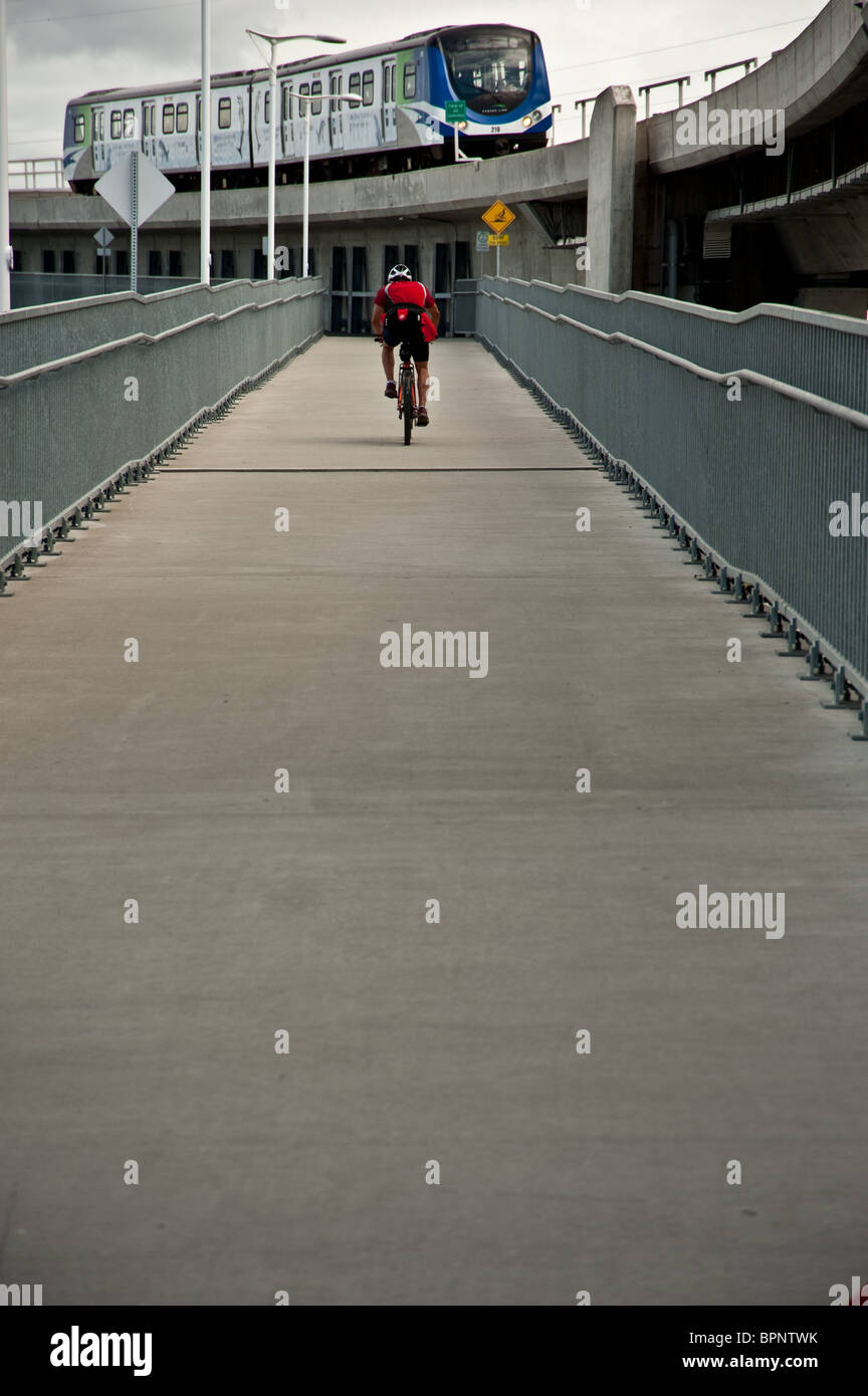 A bicyclist riding on a metro bridge over the Fraser river in Vancouver, BC Stock Photo