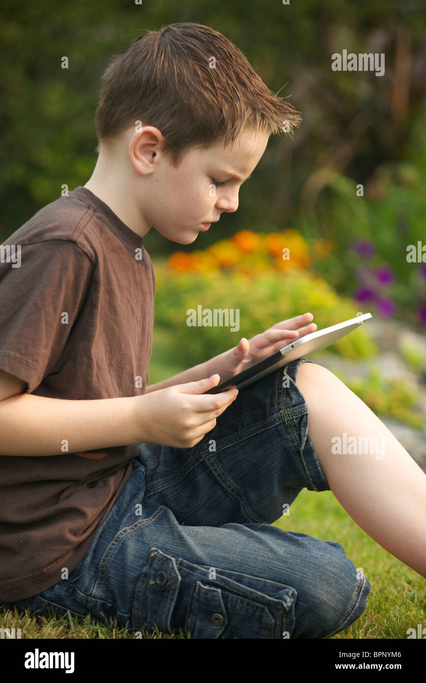 A 10 years old young boy using an iPad in the garden Stock Photo Alamy
