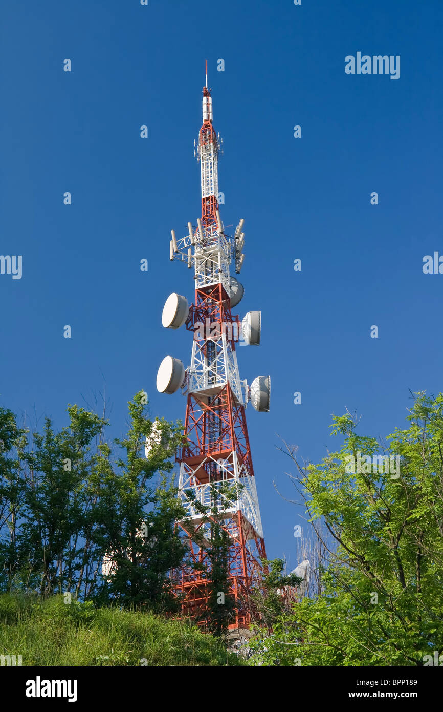 Telecommunication tower between trees above the town. The photo is taken with use of circular polarizer Stock Photo