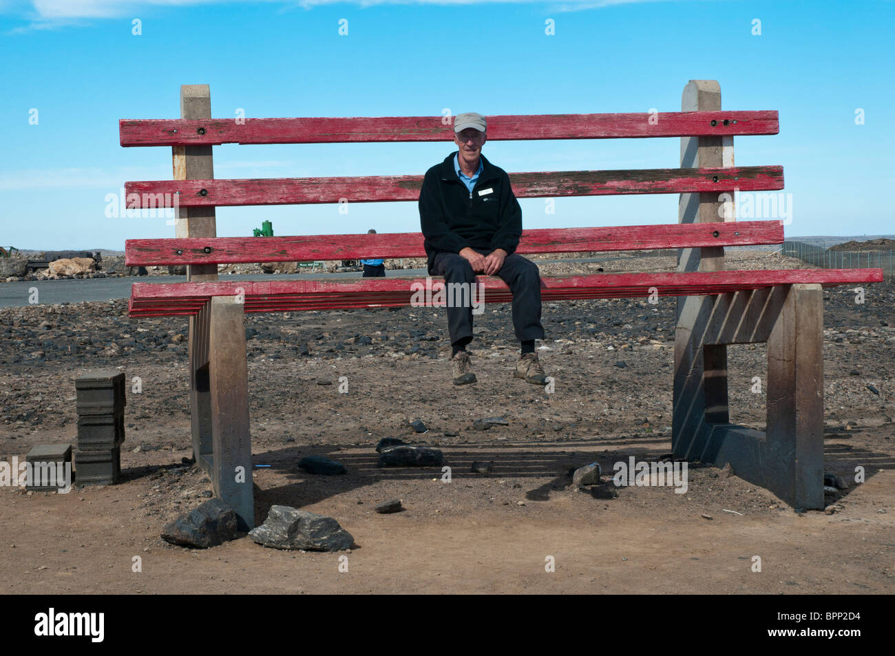 A tourist tries out a huge park bench in the New South Wales outback mining town of Broken Hill Stock Photo