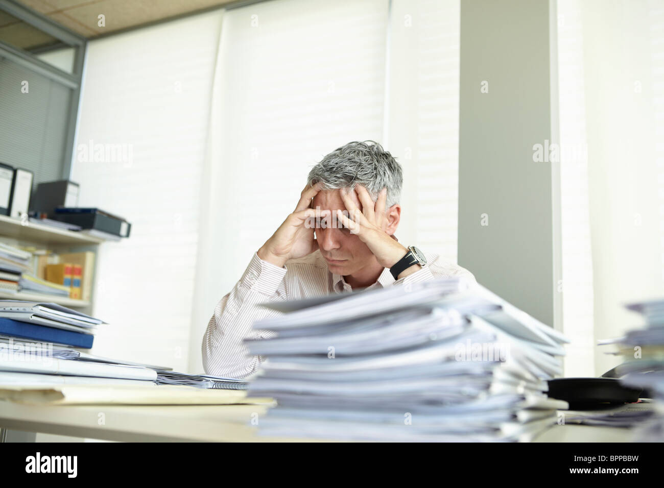 Despondent man behind desk Stock Photo