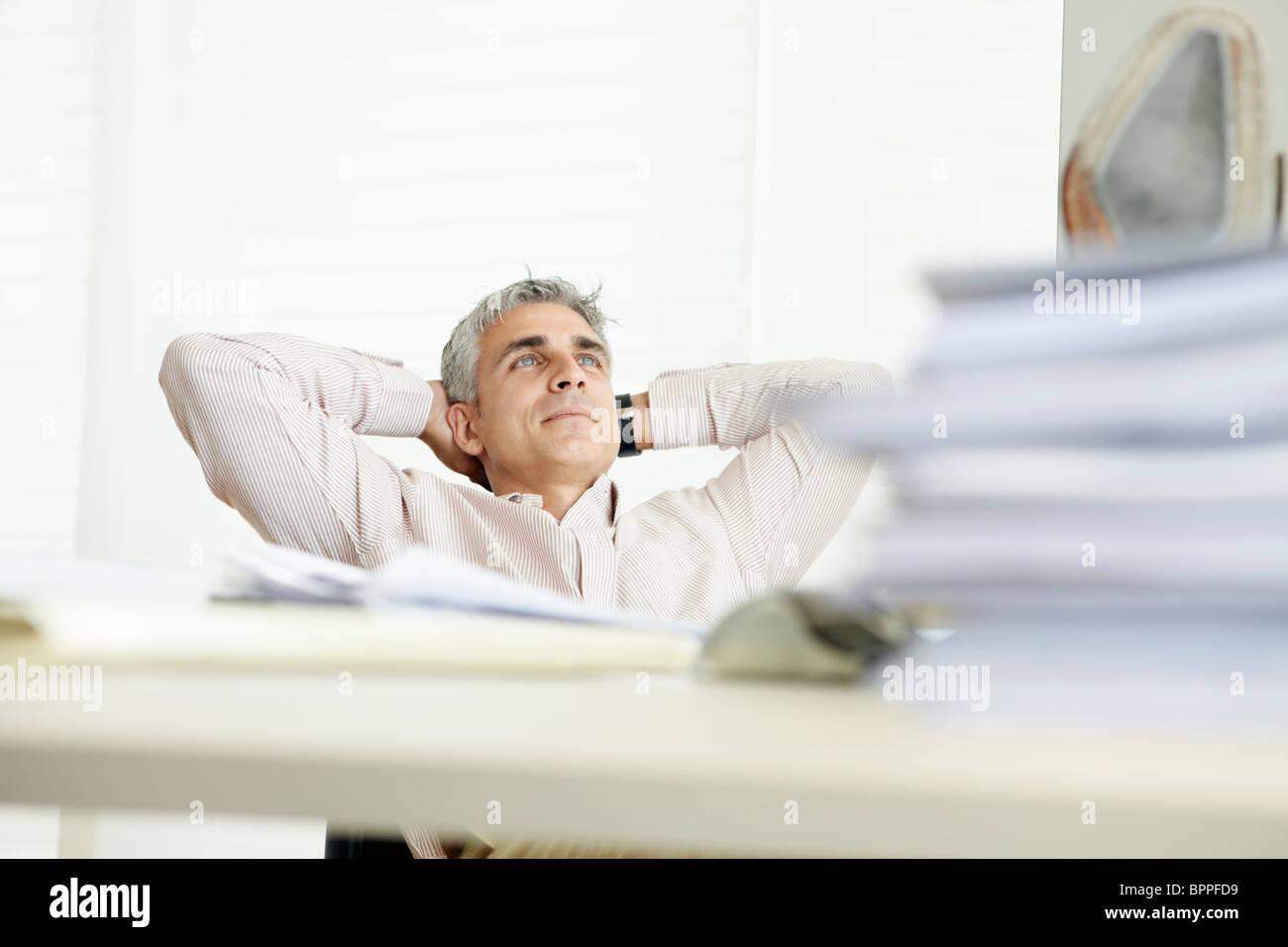 Man reclining behind desk Stock Photo