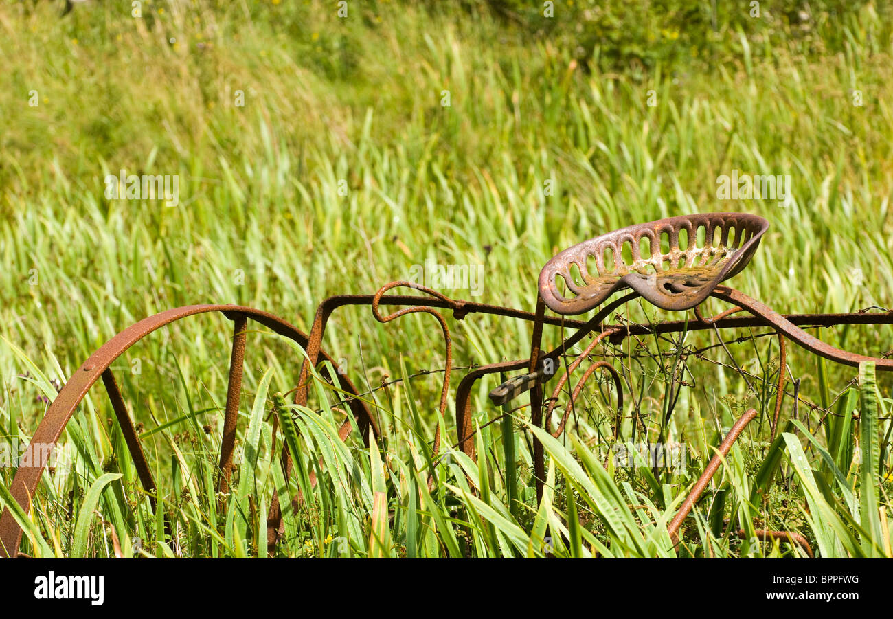 Old farming implement abandoned in a field to rust away Stock Photo