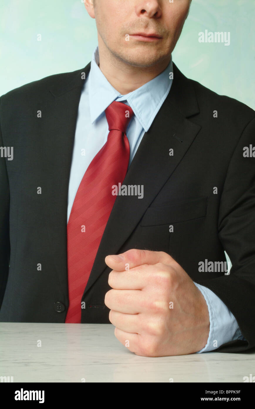 Man in a suit banging his fist on a table Stock Photo