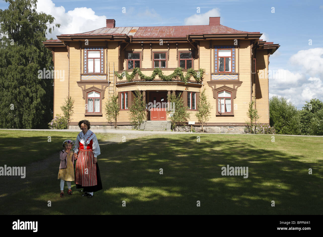 Swedish woman and girl in national folk dress in front of countryside residential building Stock Photo