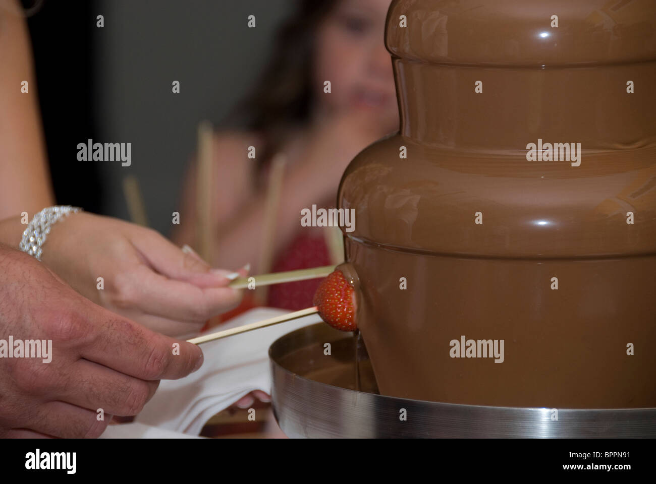 people dipping into chocolate fountain Stock Photo