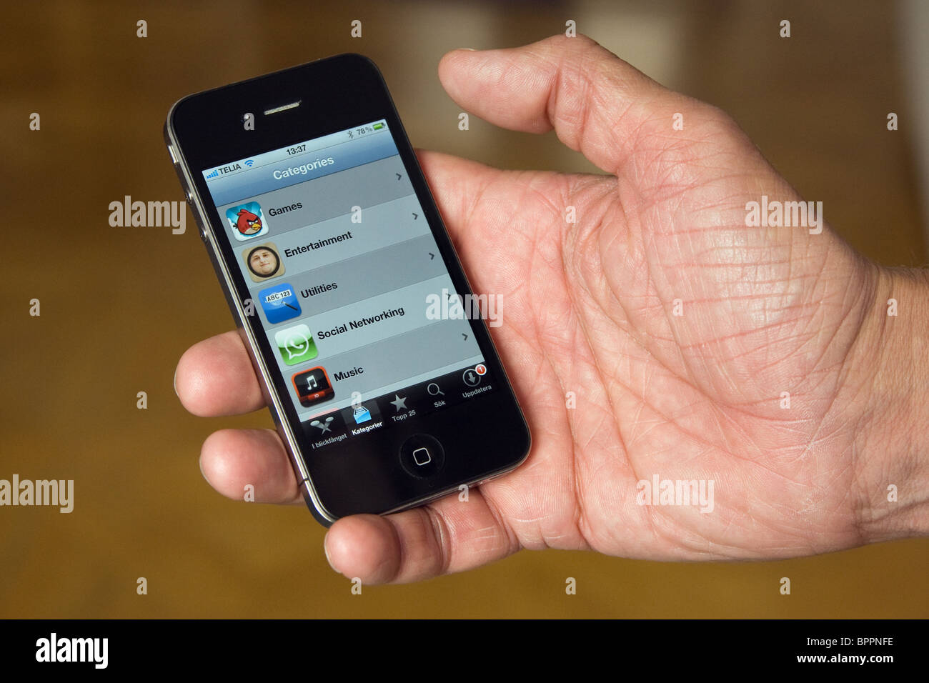 The iPhone 4 in the palm of the hand of a man. On the screen you can see the App Store. Stock Photo
