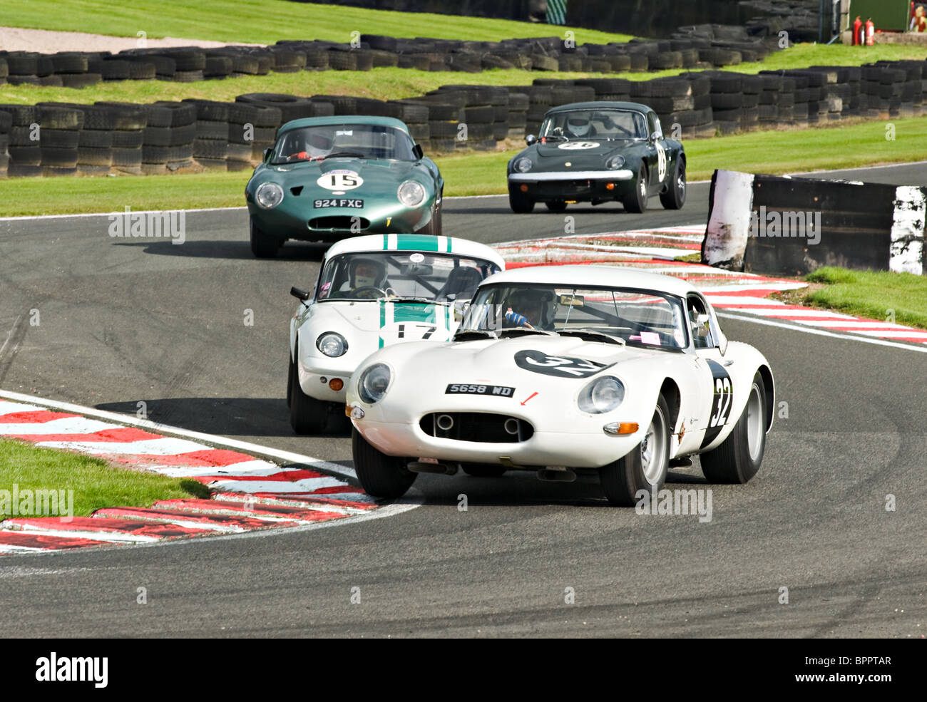 Two E Type Jaguar Race Cars and Two Lotus Elans Negotiate Brittens at Oulton Park Motor Racing Circuit Cheshire England UK Stock Photo
