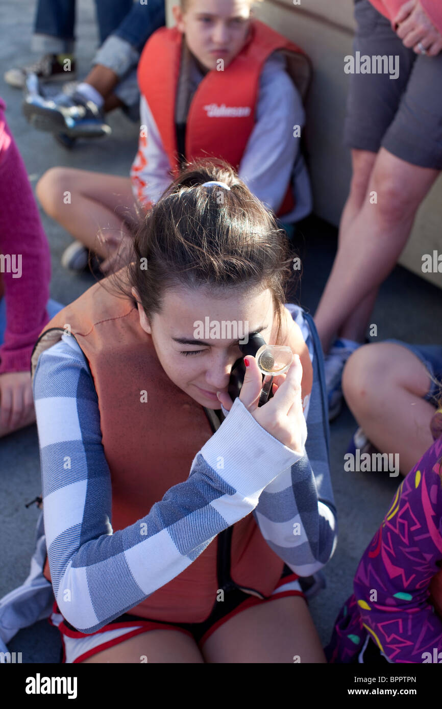 Female middle school student looks at plankton specimen during marine biology class field trip in the Gulf of Mexico Stock Photo