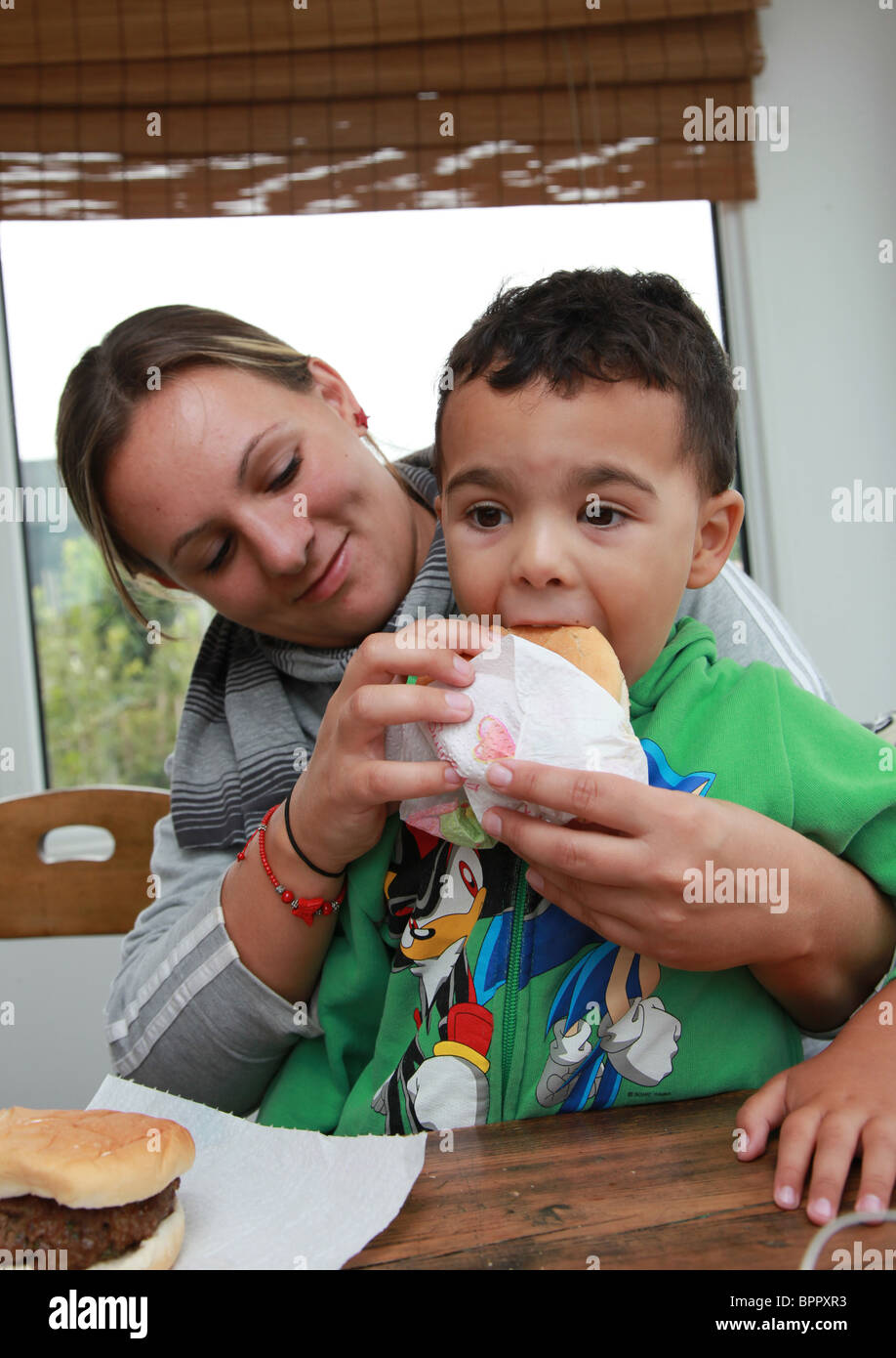 Mother feeding her toddler son hamburgers. Stock Photo